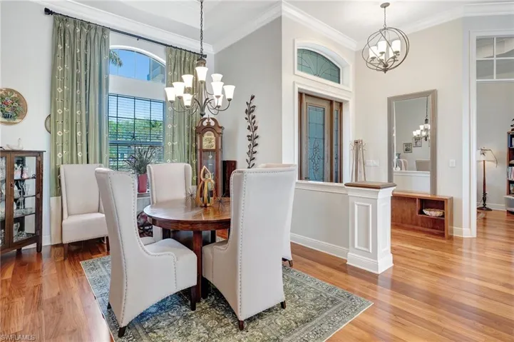 Dining area featuring ornamental molding, a notable chandelier, baseboards, and light wood finished floors