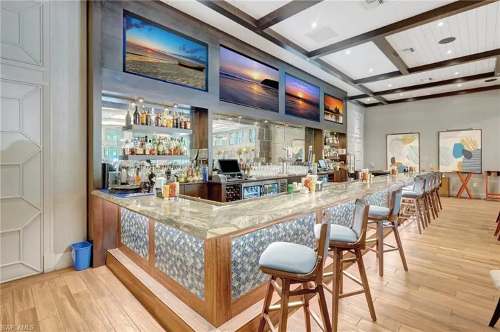 Bar with coffered ceiling, wood finished floors, a community bar, beamed ceiling, and recessed lighting