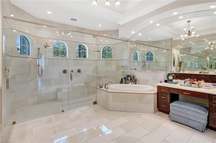 Bathroom featuring a shower stall, a garden tub, vanity, and an inviting chandelier