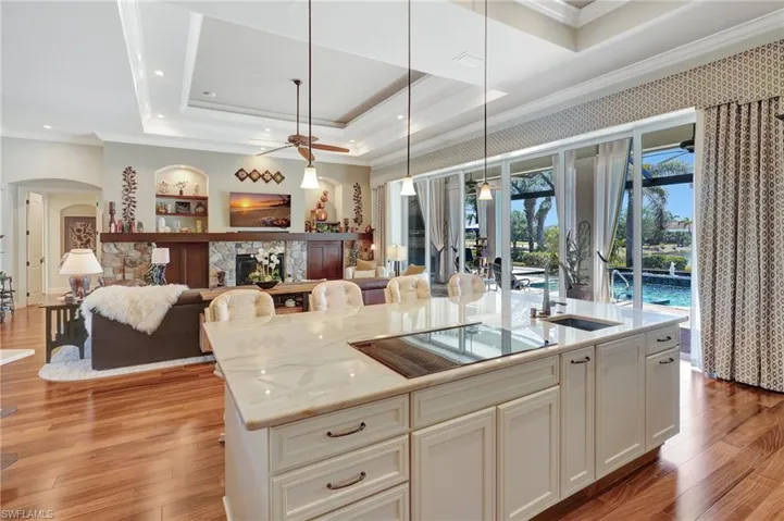 Chefs Kitchen with  extended marble counter top, a tray ceiling, a sink, black electric stovetop, open floor plan, and ceiling fan
