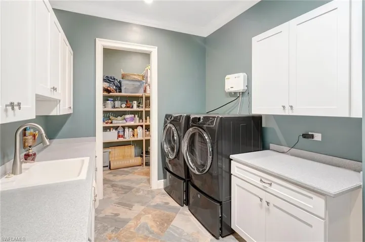 Washroom featuring cabinet space, ornamental molding, a sink, and washer and clothes dryer