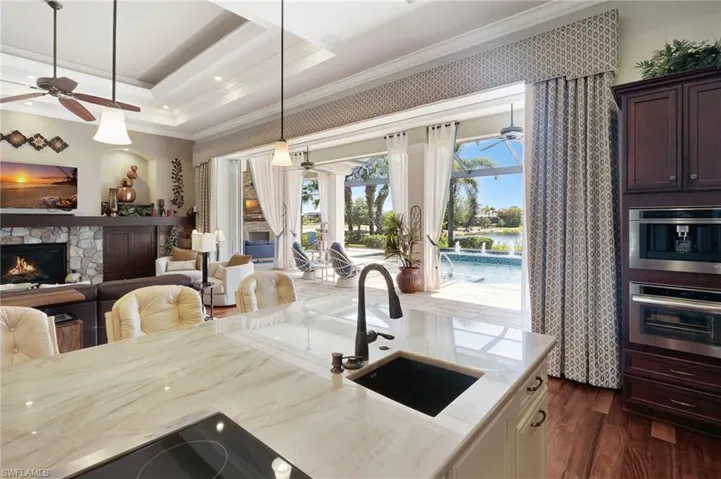 Kitchen featuring a sink, a raised ceiling, dark wood-style floors, ceiling fan, and oven