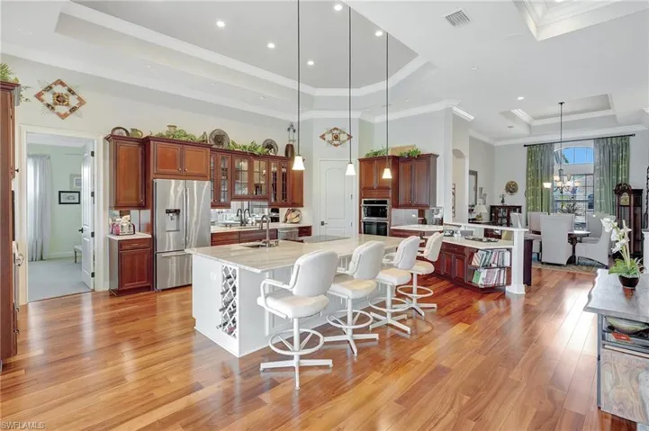 Kitchen featuring a tray ceiling, stainless steel fridge with ice dispenser, visible vents, and light wood-style floors