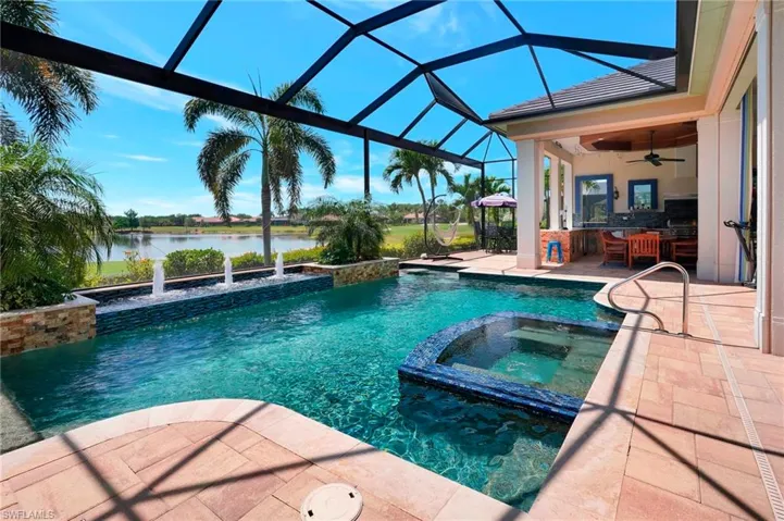 View of swimming pool featuring outdoor dry bar, a water view, ceiling fan, a pool with connected hot tub, and a patio area