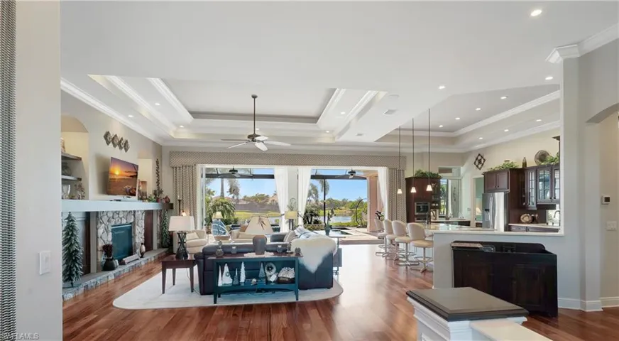 Great room with a tray ceiling, and crornamental molding, a ceiling fan, a fireplace, and wood finished floors