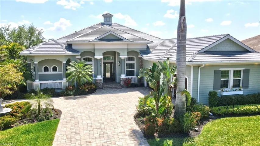 View of front facade featuring a new tile roof, a porch, and decorative driveway, and lush landscape