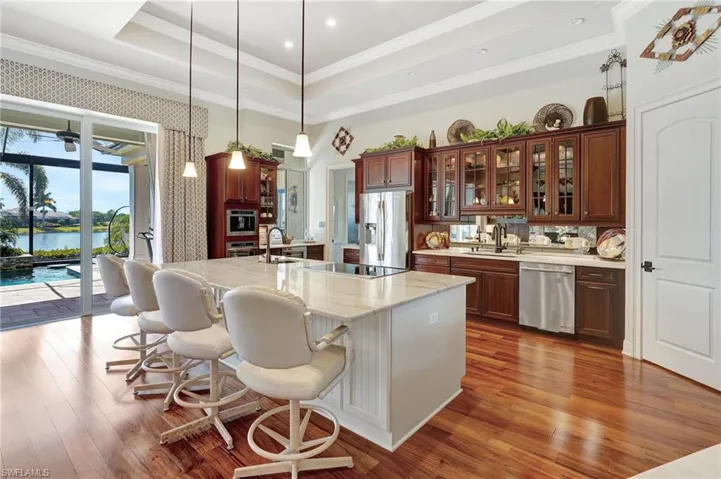 Kitchen featuring ornamental molding, stainless steel appliances, a tray ceiling, and wood finished floors