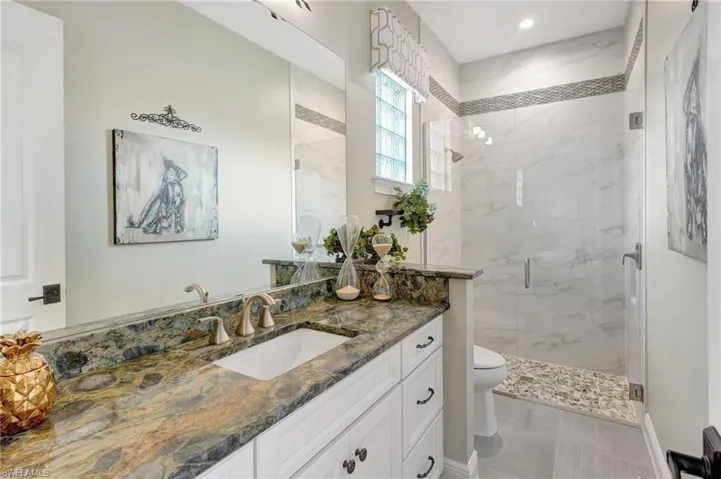 Full 2nd bathroom with recessed lighting, toilet, vanity, and a marble finish shower with frameless glass door