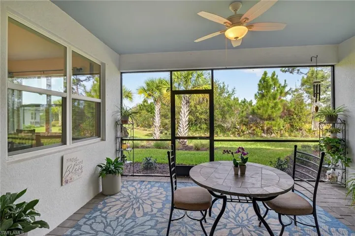 Covered screened lanai with a ceiling fan, outdoor dining space, and a patio area