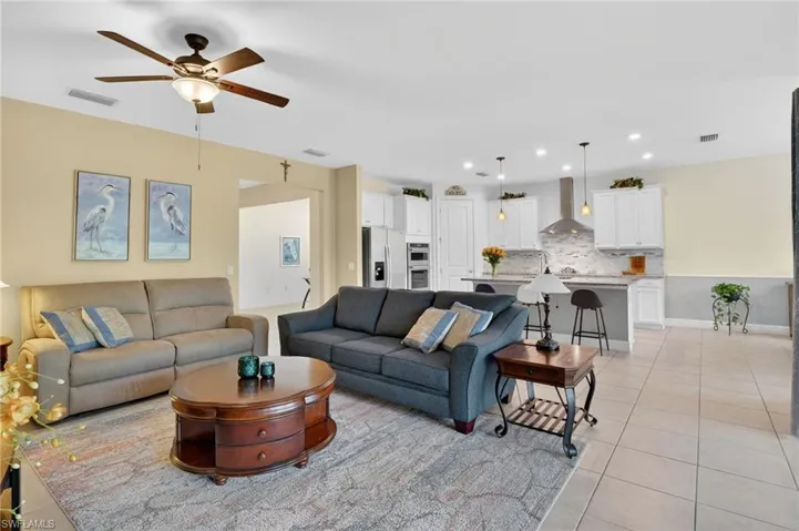 The great room features a ceiling fan and an open, inviting layout with patterned light tile floors and recessed lighting.