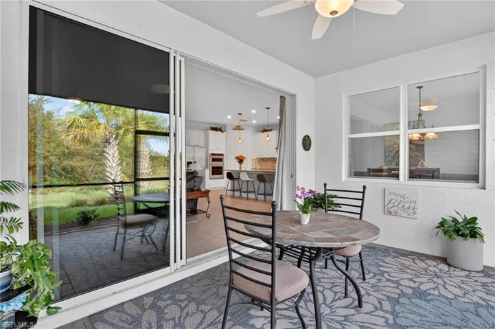 Covered screened lanai with a ceiling fan, outdoor dining space, and a patio area