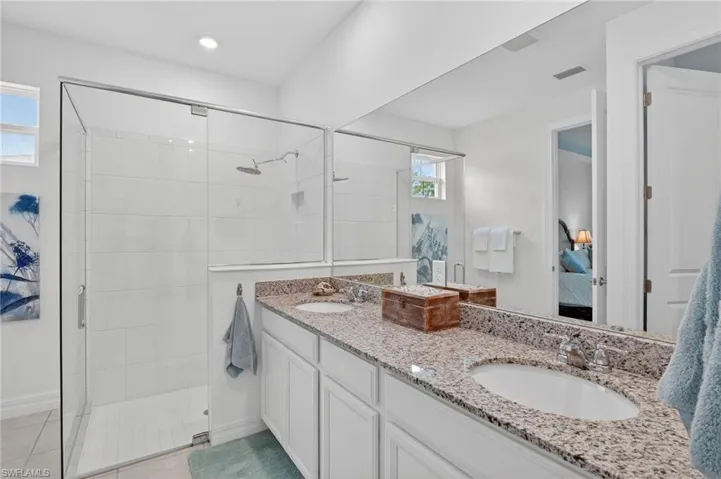 Step into a luxurious full bath that boasts a stunning double vanity, This retreat features an ensuite bathroom for added privacy and convenience, along with a sleek oversized walk-in shower stall that promises refreshing moments. The light tile patterned floors add a touch of elegance, creating a bright and inviting atmosphere that transforms your daily routine into a spa-like experience.
