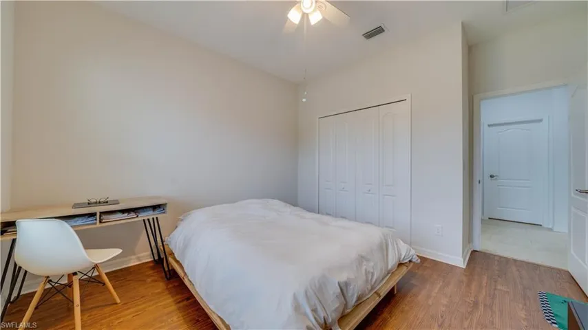 Bedroom featuring wood finished floors, a closet, ceiling fan, and a desk