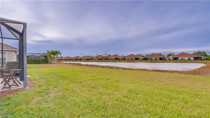 View of green lawn with a water view, a residential view, and glass enclosure