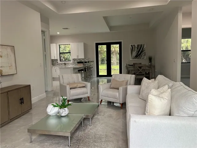 Living room featuring sink, a tray ceiling, and light tile patterned flooring