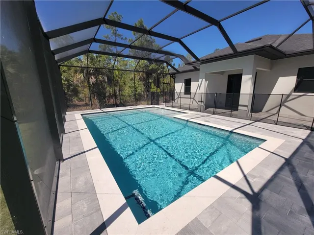Outdoor pool with a patio area, a sunroom, and glass enclosure