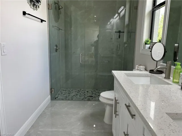 Bathroom featuring tile patterned floors, toilet, vanity, and a shower with shower door