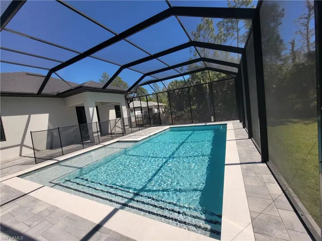 Swimming pool with glass enclosure, a patio area, and a sunroom