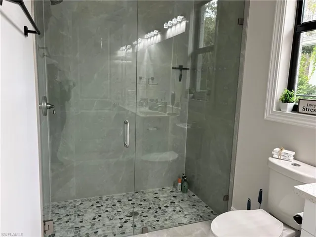 Bathroom featuring an enclosed shower, toilet, and vanity