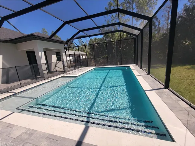 Outdoor pool featuring a lanai, a sunroom, a lawn, and a patio area