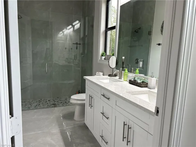 Bathroom with tile patterned floors, toilet, an enclosed shower, and vanity