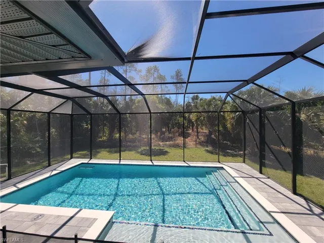 Swimming pool with a sunroom, a yard, and glass enclosure