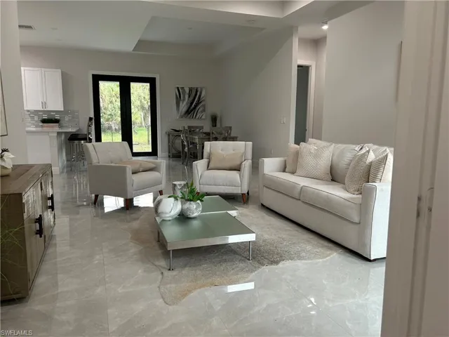 Tiled living room featuring a tray ceiling and french doors