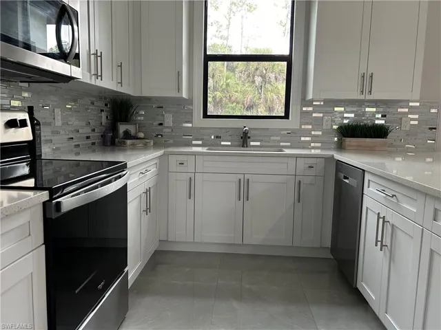 Kitchen with sink, backsplash, tile patterned floors, and appliances with stainless steel finishes