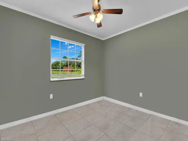 Spare room with light tile patterned flooring, crown molding, baseboards, and ceiling fan