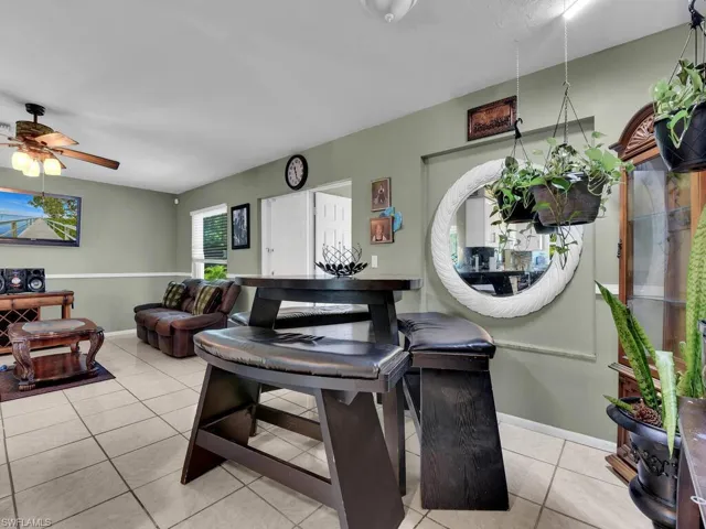 Living area featuring a ceiling fan, light tile patterned floors, and baseboards