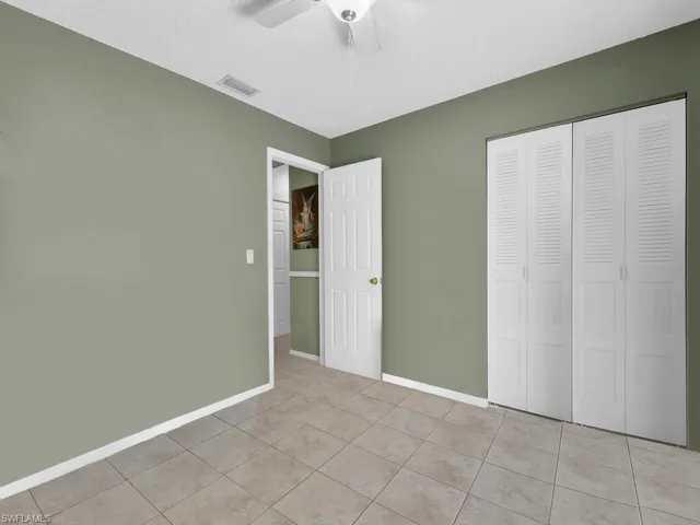 Unfurnished bedroom featuring light tile patterned floors, baseboards, ceiling fan, visible vents, and a closet