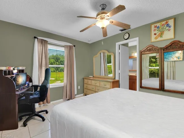 Bedroom featuring a textured ceiling, visible vents, ceiling fan, and light tile patterned floors