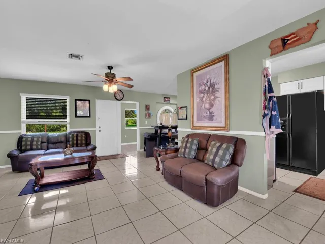 Living room with baseboards, ceiling fan, visible vents, and light tile patterned floors