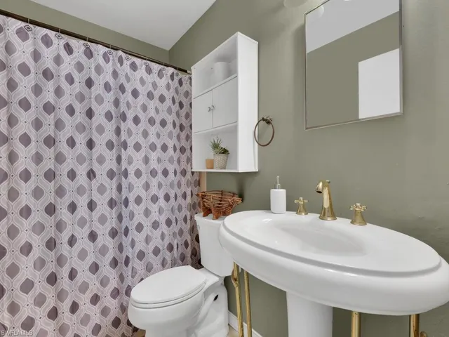 Bathroom featuring a sink, toilet, and curtained shower