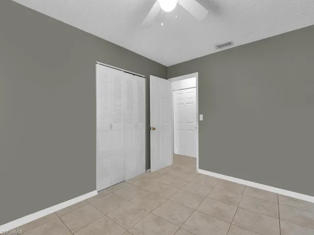 Unfurnished bedroom with light tile patterned floors, baseboards, a closet, and visible vents