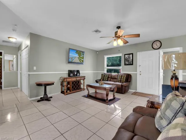 Living room with baseboards, a ceiling fan, visible vents, and light tile patterned floors