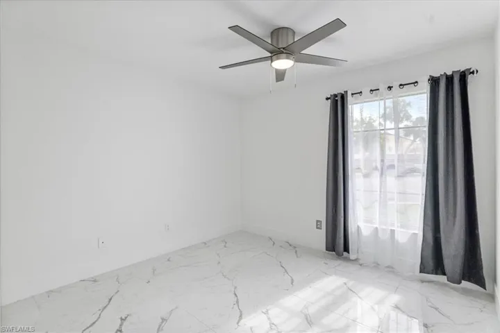 Unfurnished room with light marble finish floors and a ceiling fan