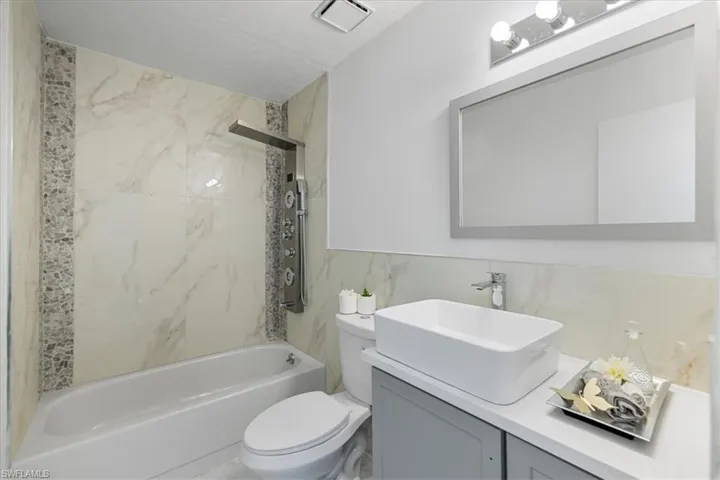 Full bath featuring vanity, shower / washtub combination, and tile walls