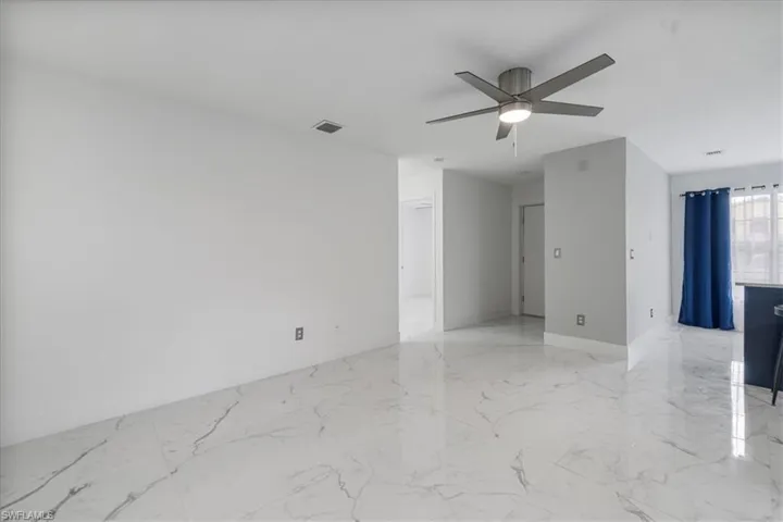 Unfurnished room with light marble finish flooring and ceiling fan