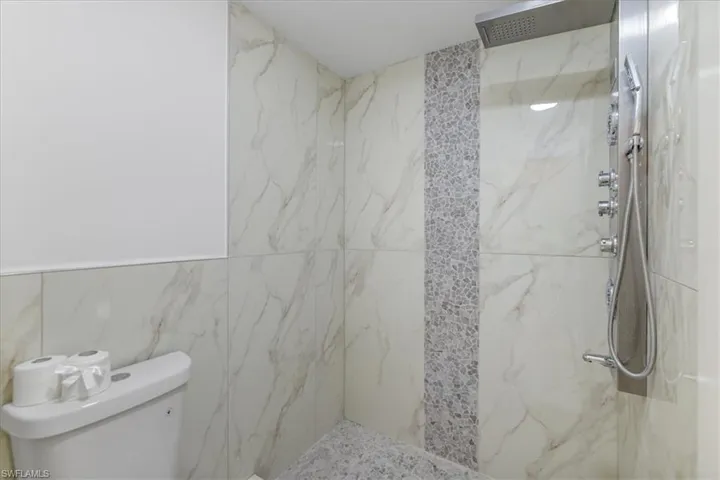 Full bath featuring a marble finish shower and tile walls