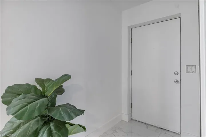 Foyer entrance with light marble finish floors and baseboards
