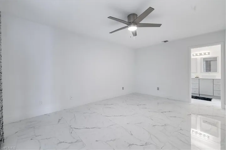 Unfurnished room with light marble finish flooring and a ceiling fan
