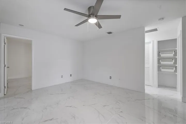 Empty room featuring light marble finish flooring and a ceiling fan