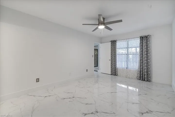 Spare room with light marble finish flooring and a ceiling fan
