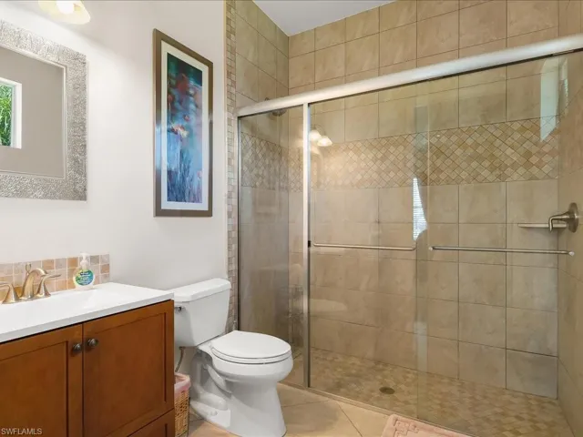 Glass-enclosed shower featuring tiled walls with a decorative accent band and a tiled floor