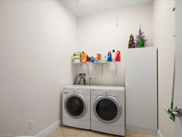 Laundry area featuring tile flooring, wall-mounted shelving, and a built-in storage cabinet