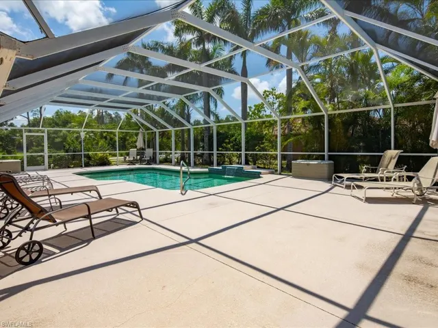 Screened-in outdoor pool area featuring a rectangular pool with integrated spa
