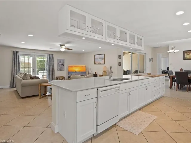 Spacious kitchen island featuring a built-in sink, white cabinetry, and a dishwasher