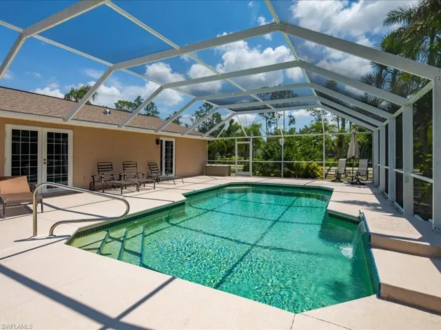Screened lanai with a rectangular swimming pool, integrated water feature, and light-colored deck