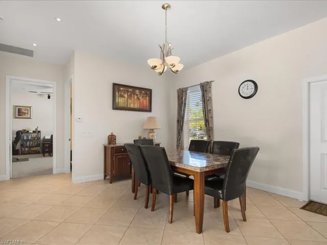 Dining area featuring a contemporary chandelier, tile flooring, and a window with blinds